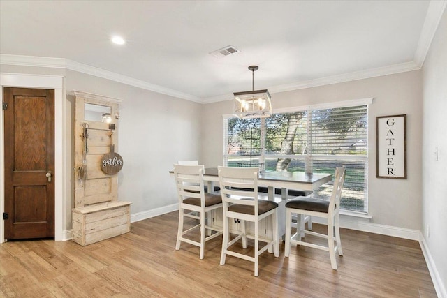 dining space with crown molding, light hardwood / wood-style floors, and a notable chandelier