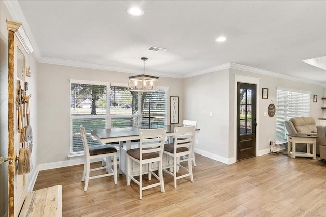 dining area with an inviting chandelier, light hardwood / wood-style flooring, and crown molding