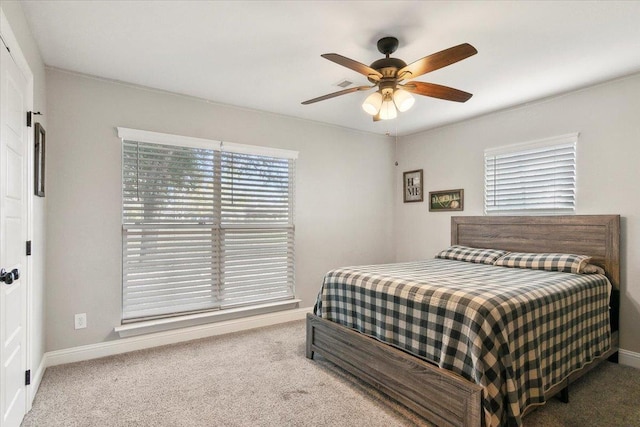 bedroom with multiple windows, ceiling fan, and carpet