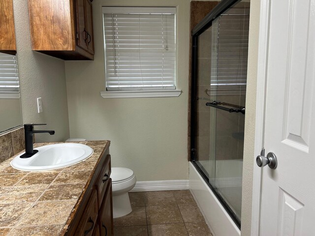 full bathroom featuring combined bath / shower with glass door, vanity, and toilet