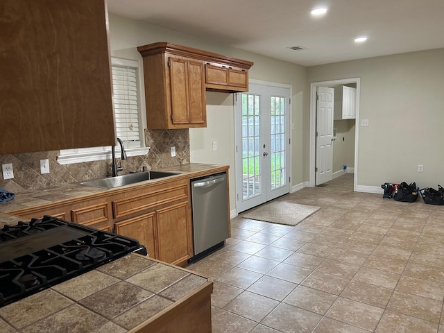 kitchen featuring tile countertops, french doors, sink, stainless steel dishwasher, and tasteful backsplash