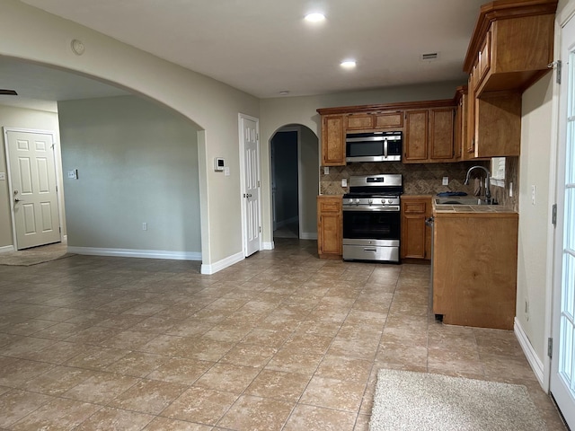 kitchen featuring decorative backsplash, appliances with stainless steel finishes, and sink