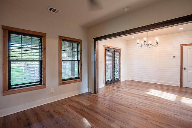 unfurnished dining area with wood-type flooring and an inviting chandelier