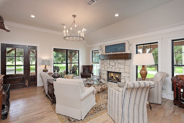 living room with a stone fireplace, a healthy amount of sunlight, lofted ceiling, and an inviting chandelier