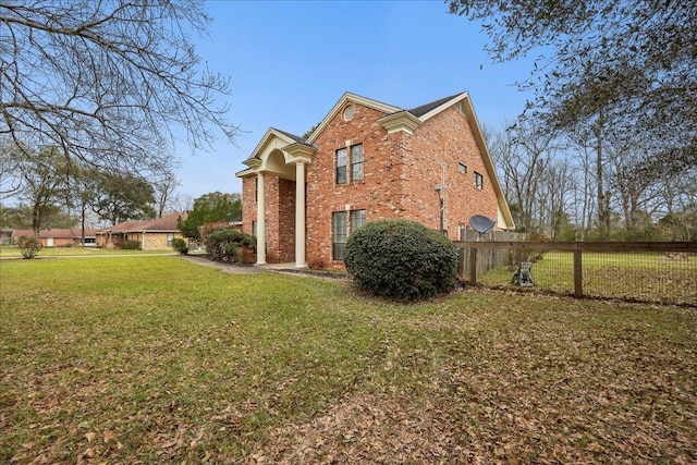 view of property exterior featuring brick siding, a yard, and fence