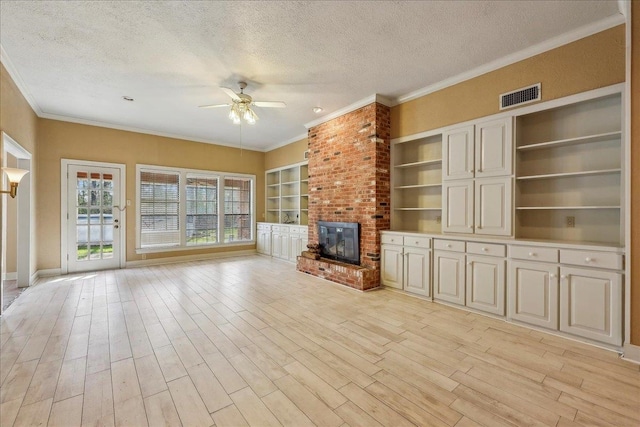 unfurnished living room featuring a brick fireplace, visible vents, light wood-style floors, and a textured ceiling