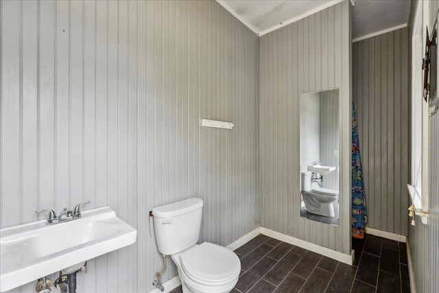 bathroom with wood tiled floor, baseboards, a sink, and toilet