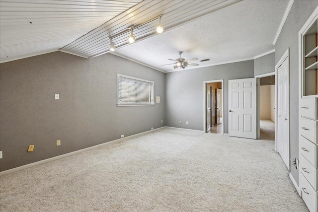 unfurnished bedroom with a textured ceiling, light colored carpet, visible vents, baseboards, and crown molding