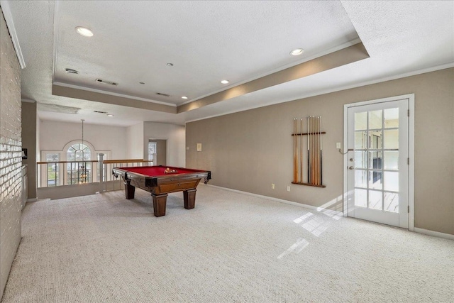 rec room featuring a textured ceiling, ornamental molding, carpet, and a raised ceiling