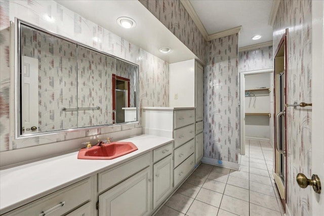 bathroom with tile patterned flooring, vanity, baseboards, a walk in closet, and wallpapered walls
