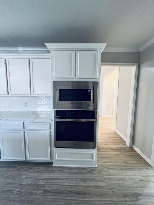 7060 Westgate Dr, Beaumont, TX 77706 - kitchen view of stainless steel appliances, crown molding, light countertops, white cabinets, and wood finished floors