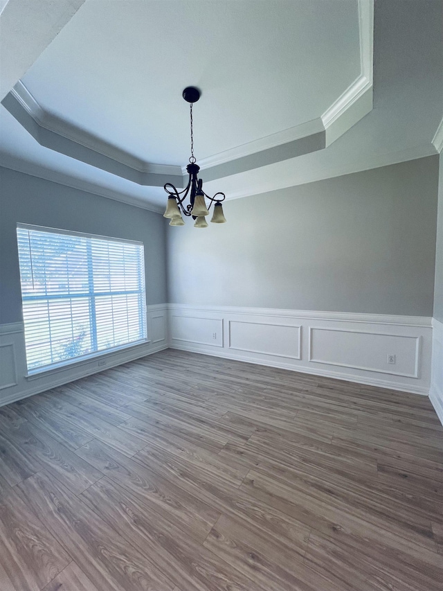 7060 Westgate Dr, Beaumont, TX 77706 - spare room featuring a raised ceiling, a chandelier, crown molding, wood finished floors, and a wainscoted wall