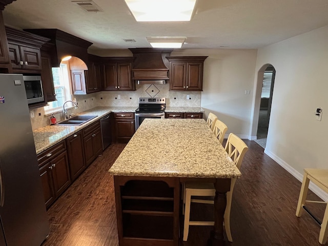 kitchen featuring sink, a center island, a breakfast bar, appliances with stainless steel finishes, and custom exhaust hood