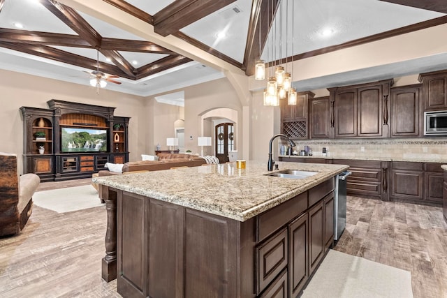 8395 Carrie Ln, Beaumont, TX 77713 - kitchen with arched walkways, dark brown cabinets, a center island with sink, light wood-type flooring, and beamed ceiling