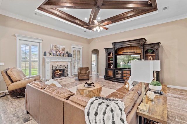 8395 Carrie Ln, Beaumont, TX 77713 - living room with arched walkways, a warm lit fireplace, ornamental molding, a ceiling fan, and coffered ceiling