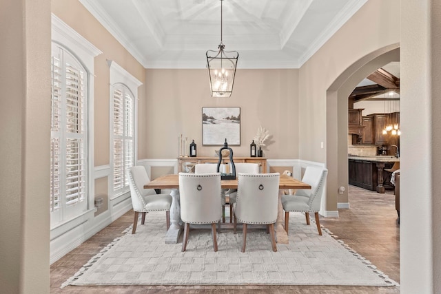 8395 Carrie Ln, Beaumont, TX 77713 - dining area with a chandelier, arched walkways, light wood-type flooring, a raised ceiling, and crown molding