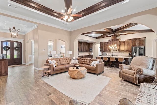 8395 Carrie Ln, Beaumont, TX 77713 - living room with arched walkways, a chandelier, ornamental molding, and light wood-type flooring