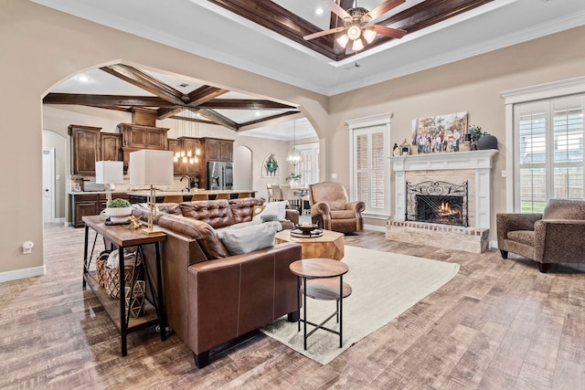 8395 Carrie Ln, Beaumont, TX 77713 - living room with arched walkways, a chandelier, a fireplace, a ceiling fan, and beamed ceiling