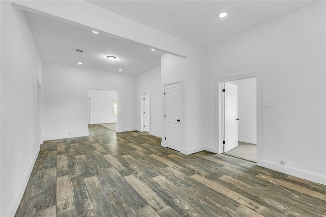 empty room with a towering ceiling and dark hardwood / wood-style floors