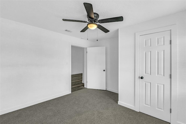 unfurnished bedroom featuring dark colored carpet, ceiling fan, and a closet