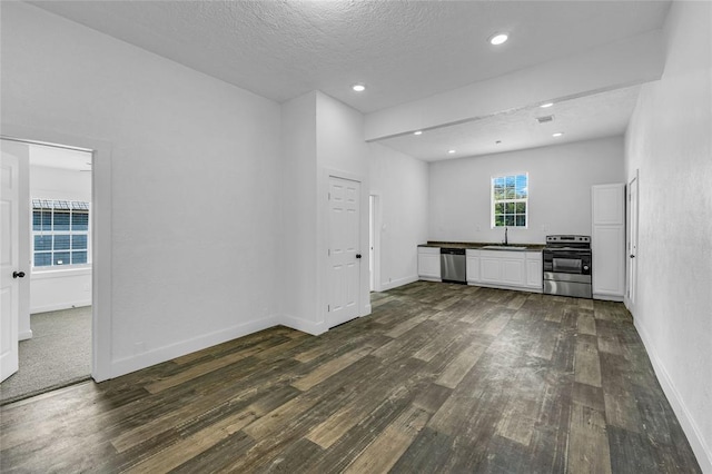 unfurnished living room featuring sink, dark hardwood / wood-style flooring, and a textured ceiling