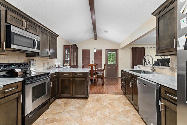 6690 Hackberry Dr, Beaumont, TX 77708 - kitchen featuring appliances with stainless steel finishes, a peninsula, a sink, light countertops, and dark brown cabinets