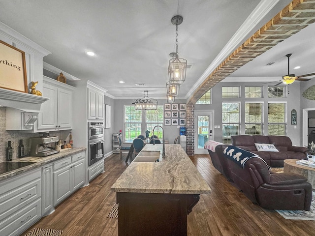 kitchen featuring open floor plan, ornamental molding, dark wood finished floors, and tasteful backsplash