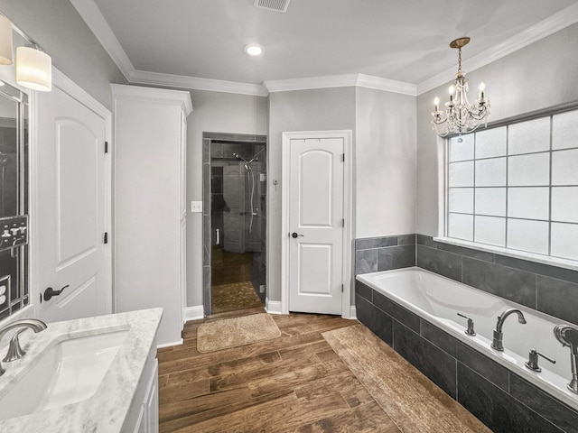 full bath with a garden tub, wood finished floors, vanity, ornamental molding, and a stall shower