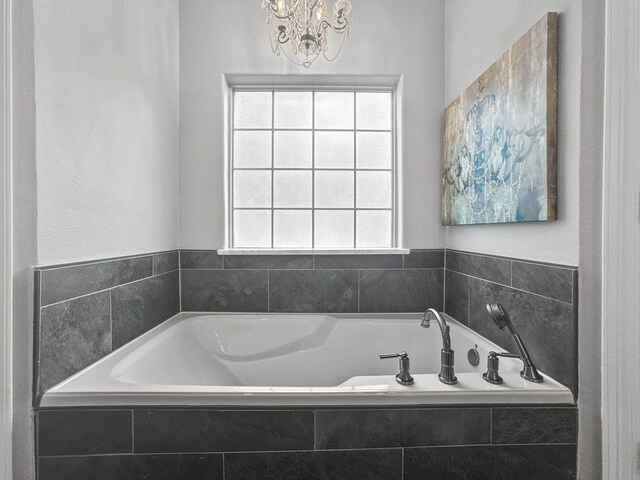 bathroom featuring a garden tub and an inviting chandelier