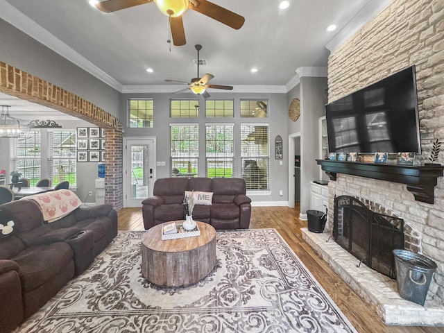 living area featuring a fireplace, visible vents, ornamental molding, wood finished floors, and baseboards