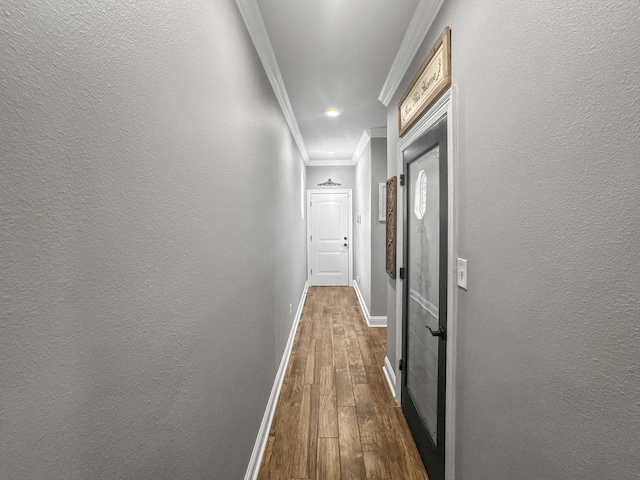 hallway featuring crown molding, a textured wall, dark wood-type flooring, and baseboards