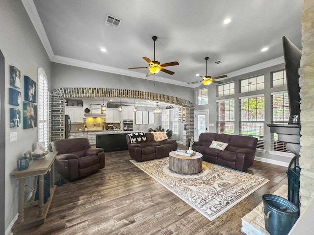 living area featuring baseboards, visible vents, dark wood-style flooring, and crown molding