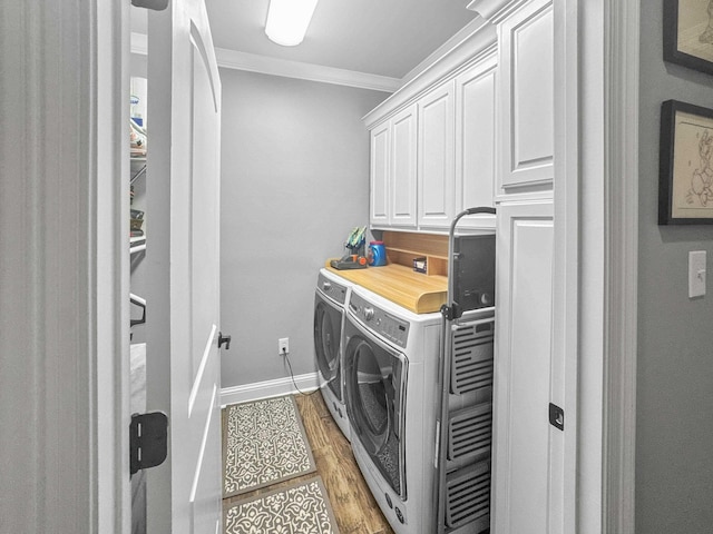 laundry room with baseboards, cabinet space, light wood finished floors, washer and clothes dryer, and crown molding