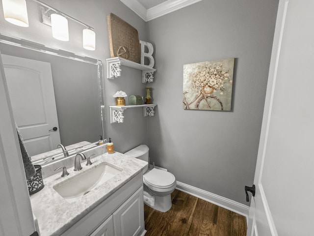 half bath with toilet, ornamental molding, vanity, wood finished floors, and baseboards