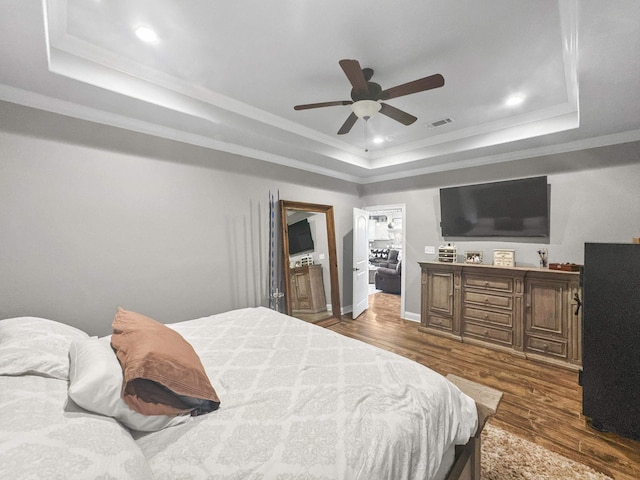 bedroom with visible vents, a tray ceiling, dark wood-style flooring, and ornamental molding