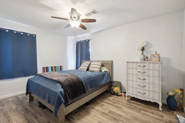 bedroom featuring visible vents, baseboards, ceiling fan, and wood finished floors