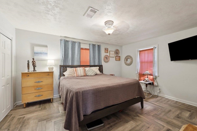 bedroom with visible vents, a textured ceiling, and baseboards