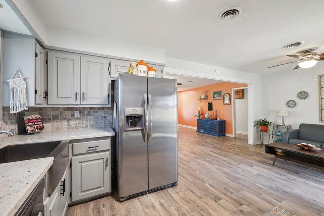 kitchen featuring tasteful backsplash, visible vents, stainless steel fridge, and light wood-style flooring