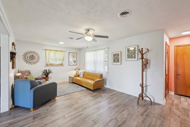 living room featuring visible vents, a ceiling fan, light wood-type flooring, and baseboards