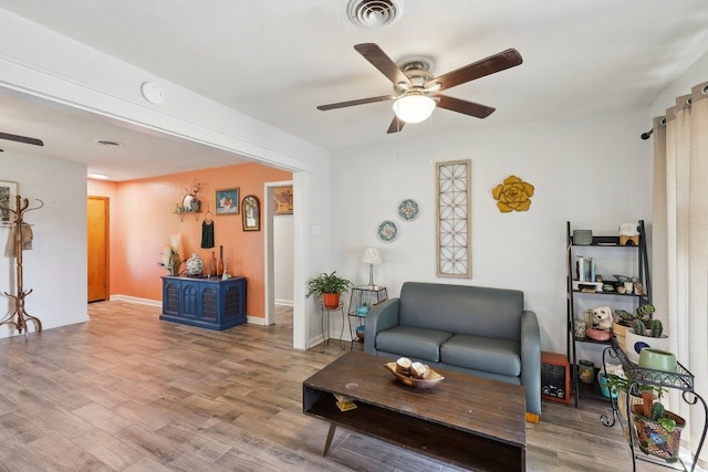 living area featuring visible vents, baseboards, a ceiling fan, and wood finished floors