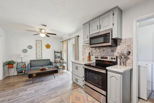 kitchen featuring visible vents, a ceiling fan, tasteful backsplash, stainless steel appliances, and light wood-style floors