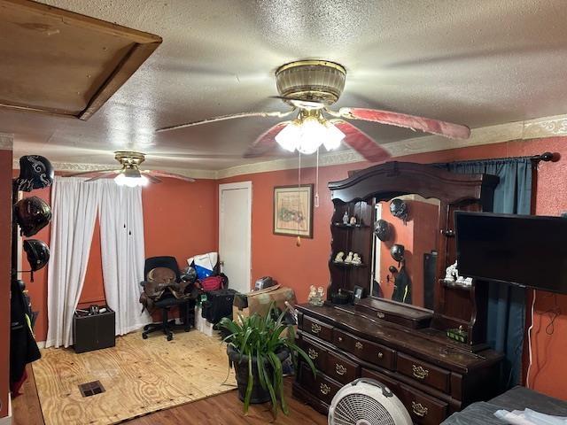 bedroom with ceiling fan, wood-type flooring, and a textured ceiling