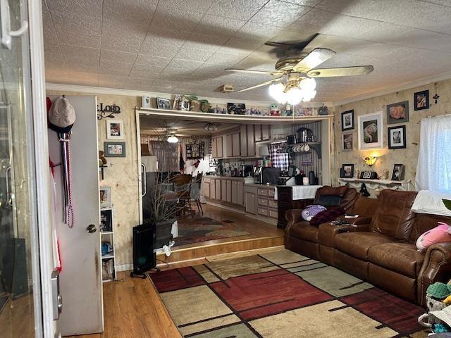 living room with hardwood / wood-style floors, ceiling fan, and ornamental molding