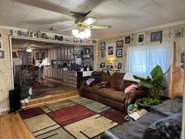 living room with crown molding, ceiling fan, and wood-type flooring