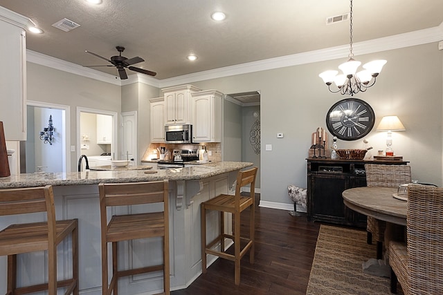3665 Canyon Ln, Beaumont, TX 77713 - kitchen with stainless steel appliances, dark wood-type flooring, a ceiling fan, light stone countertops, and a breakfast bar area