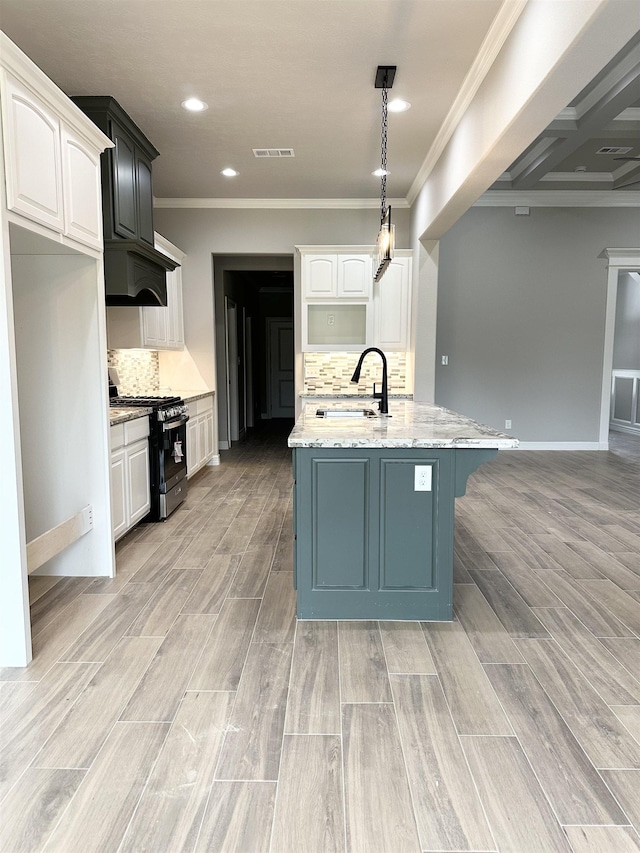 kitchen featuring light stone countertops, white cabinetry, sink, and gas range