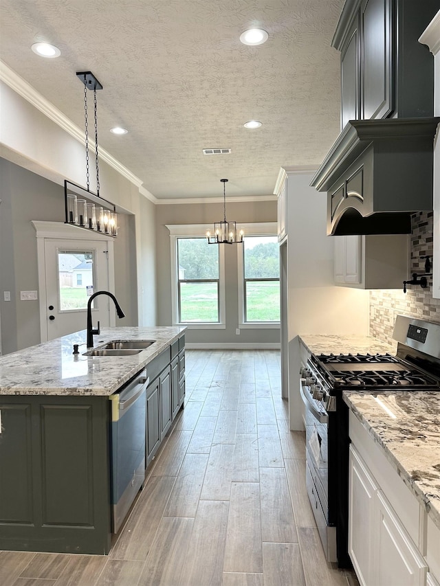 kitchen with white cabinets, pendant lighting, a kitchen island with sink, and appliances with stainless steel finishes