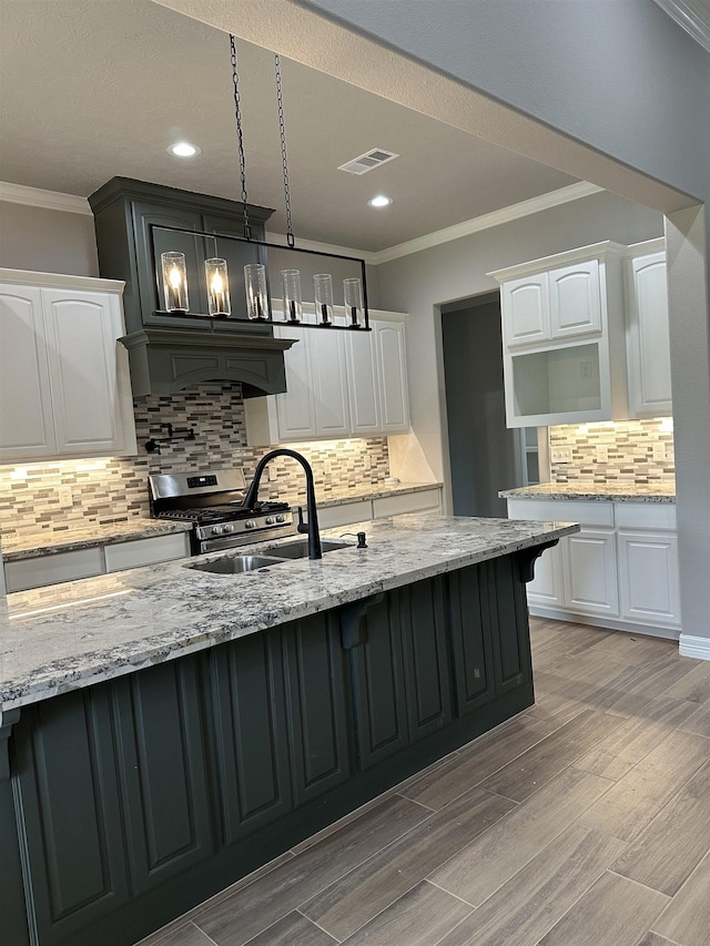 kitchen with light stone counters, ornamental molding, sink, pendant lighting, and white cabinetry