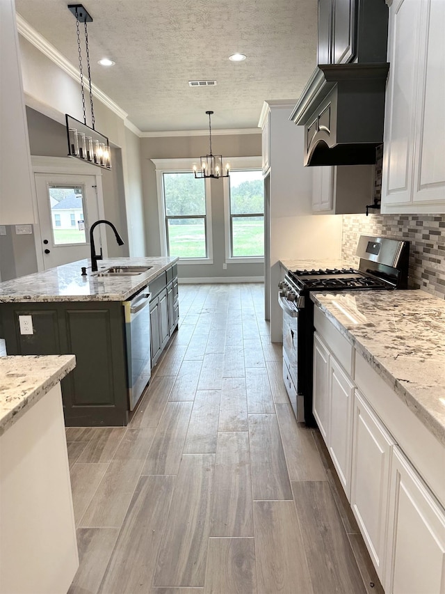 kitchen featuring white cabinets, pendant lighting, stainless steel appliances, and a kitchen island with sink