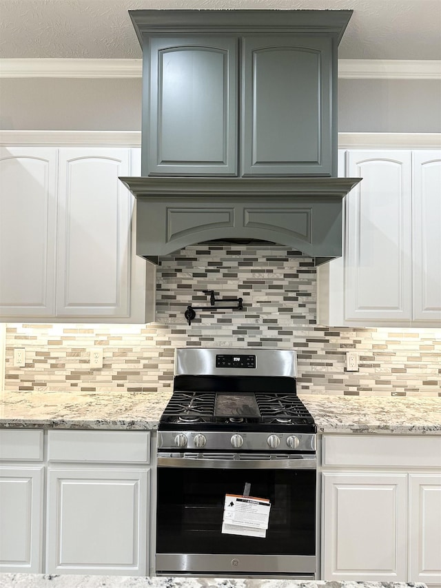 kitchen featuring white cabinets, gas stove, crown molding, and backsplash